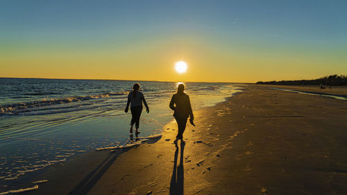 People walking on beach during sunset