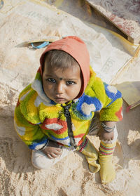High angle portrait of baby boy wearing warm clothing while sitting outdoors