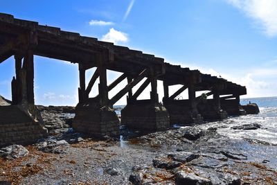 Bridge over sea shore against sky