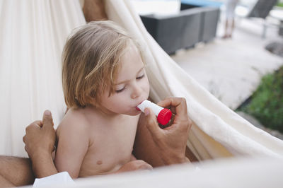 Cropped image of father examining illness with equipment while lying on hammock