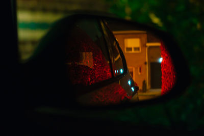 Reflection of man photographing on side-view mirror