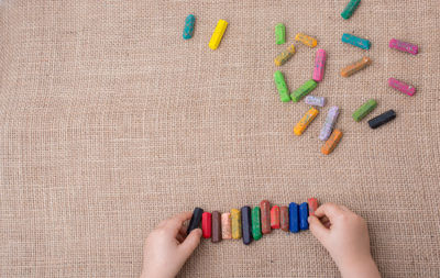Cropped hands holding crayons on burlap