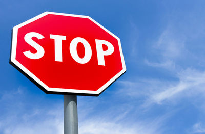 Low angle view of road sign against blue sky