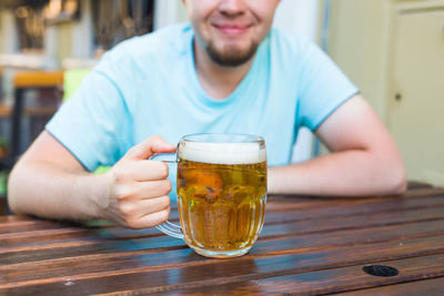 Midsection of man drinking glass on table