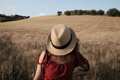 Woman with hat standing on field against sky