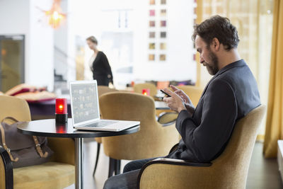 Side view of businessman using mobile phone in hotel restaurant