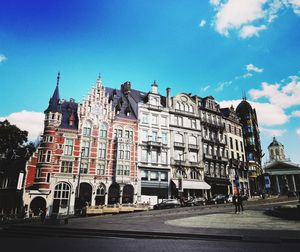 Street by buildings in city against sky