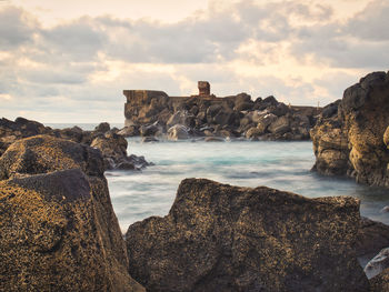 Rock formations by sea against sky