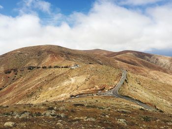 Scenic view of road by mountains against sky