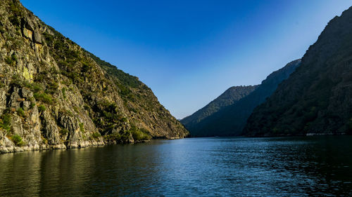 Scenic view of lake and mountains against clear blue sky