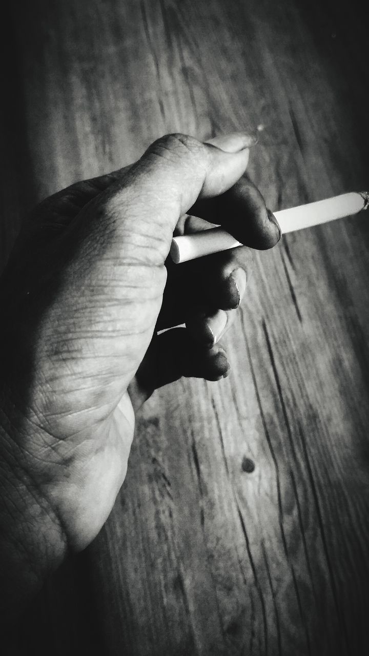 CLOSE-UP OF HANDS HOLDING CIGARETTE