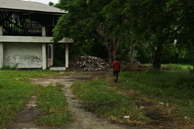 Rear view of person walking on footpath by building