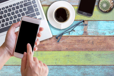 Cropped image of hand holding coffee cup on table
