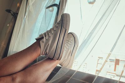 Low section of woman relaxing on window