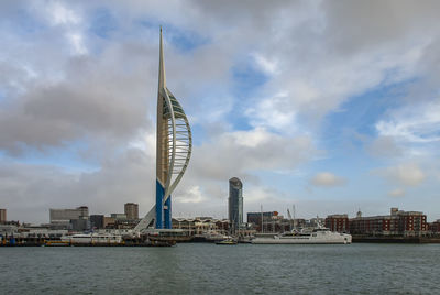 Sea by city buildings against sky