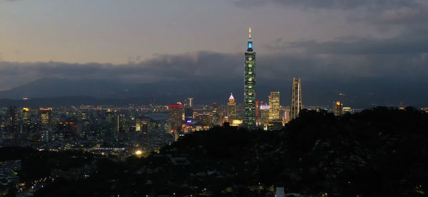 Illuminated buildings in city against sky at night