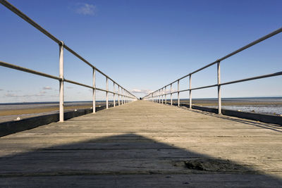 Footbridge over sea against clear sky