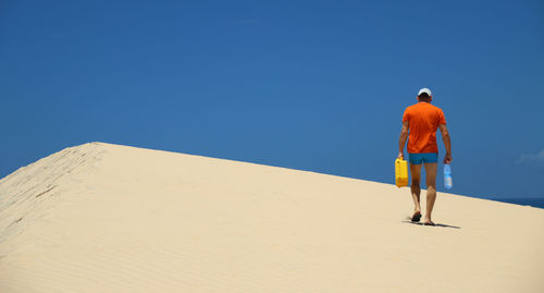 Rear view of man standing on sand dune