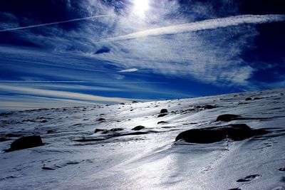 Snow covered landscape against blue sky