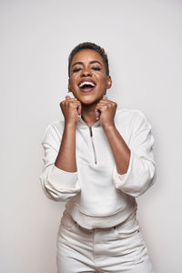 Positive young african american female in stylish apparel with makeup and short hair on light background