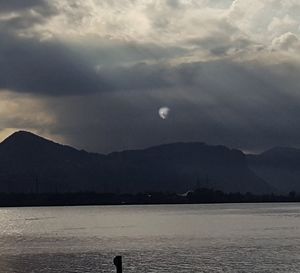 Scenic view of lake and mountains against dramatic sky