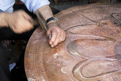 Cropped hands of man carving metal