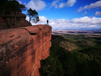 Man standing on cliff against sky