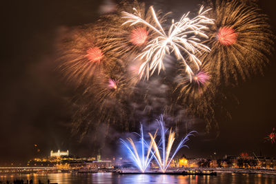 Low angle view of firework display over city at night