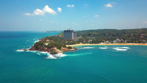 Scenic view of sea by buildings against blue sky