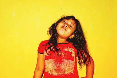 Portrait of a girl standing against yellow wall