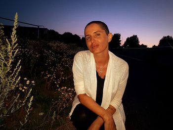 Portrait of smiling woman standing by tree against sky