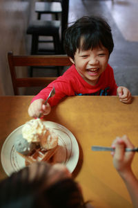 Cute boy smiling while sitting on table