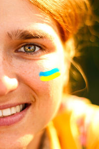 Ukrainian woman. ukrainian flag on the cheeks. selfie of a young woman 20, 25 years old. half face