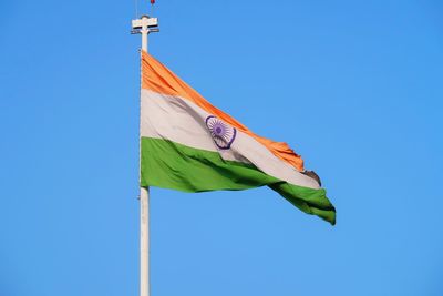 Low angle view of flag against blue sky