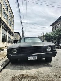 Cars on road by buildings against sky