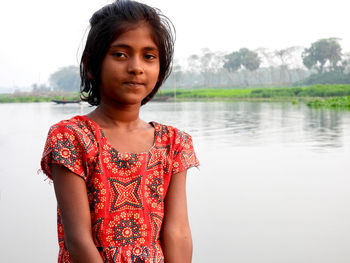 Portrait of young woman standing against lake