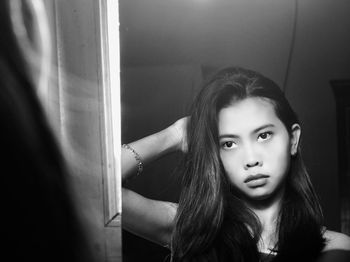 Young woman with long hair looking in mirror at home