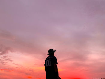 Silhouette man standing against orange sky