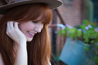 Happy woman with long hair wearing hat looking down