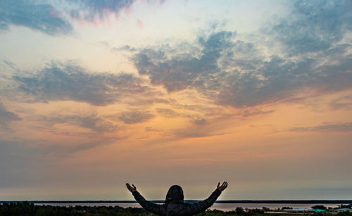 Silhouette person by tree against sky during sunset