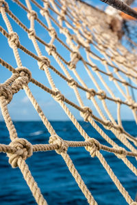 Close-up of rope net against sea and sky