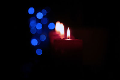 Close-up of illuminated candles in darkroom