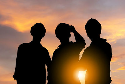 Silhouette people standing against sky during sunset