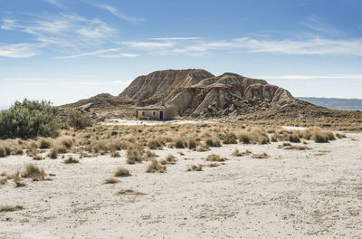 Scenic view of house on desert field against rock formations