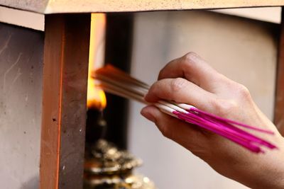 Cropped hand of woman igniting incenses