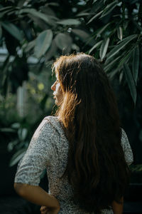 A rear view of a young woman amidst plants during sunset