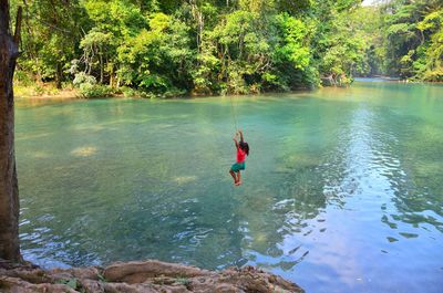 Rear view of man jumping in lake