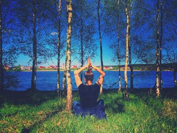 Rear view of woman standing by lake against sky