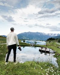 Rear view of man standing by lake against sky