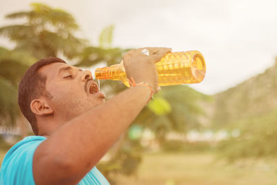 Side view portrait of a young man drinking outdoors